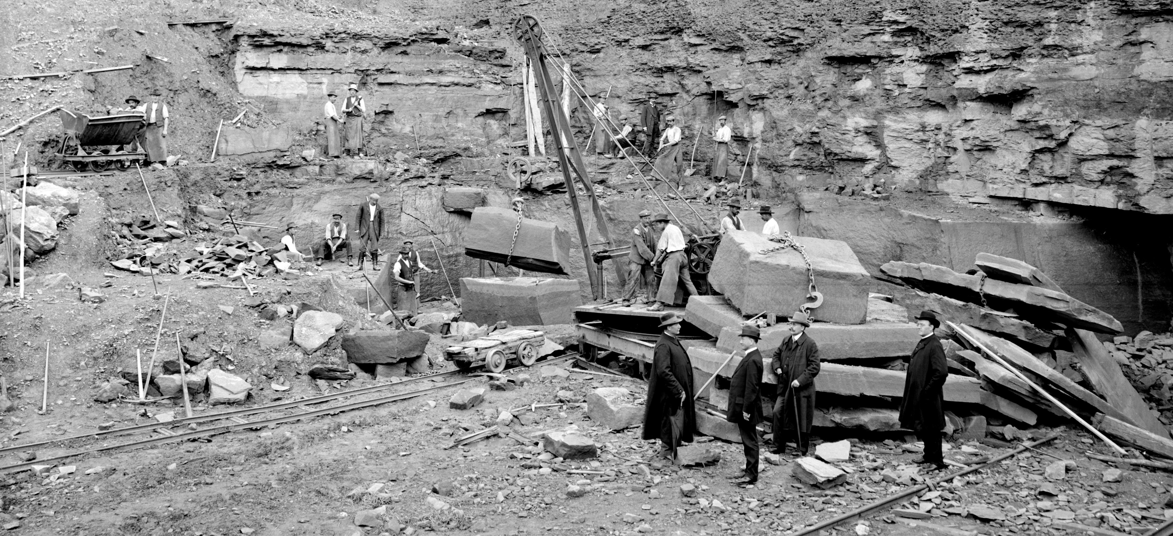 Blick in einen historischen Steinbruch mit Männern bei der Arbeit